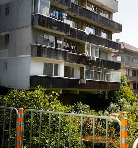The yard of a block with glazed balconies, washing hung out and green bushes in front